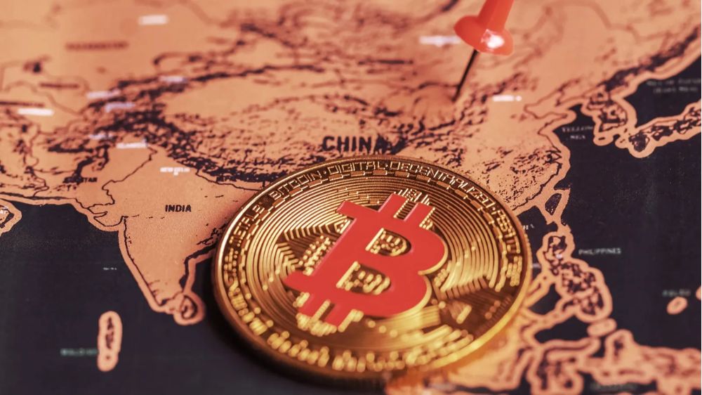یک سکه بیت کوین روی نقشه‌ای که کشور چین روی آن پین شده