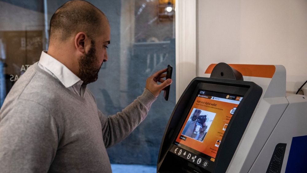یک مرد میانسال در حال استفاده از دستگاه Bitcoin ATM