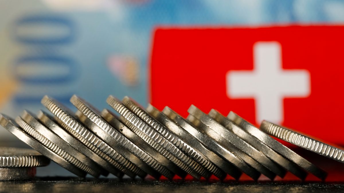 سکه‌های فرانک سوئیس و پرچم این کشور نشان‌دهنده‌ی شرایط اقتصادی