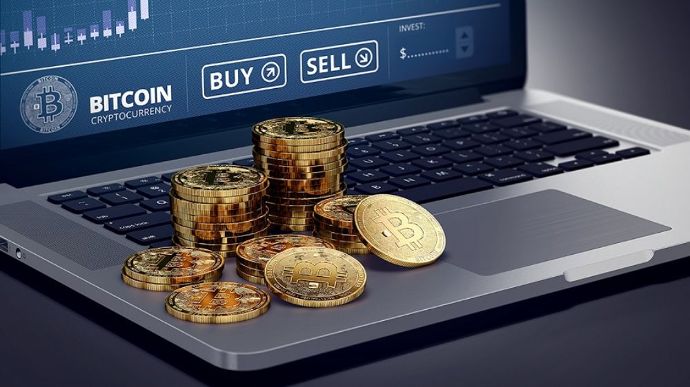 سکه‌های طلایی بیت کوین روی یک لپتاپ در حال انجام معامله