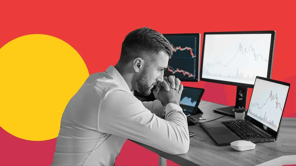 مردی پشت چند نمایشگر در حالی که از ترید بیش از حد یا overtrading خسته شده است.