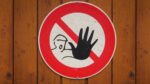 علامت هشدار و دست نگه داشتن روی دیوار چوبی