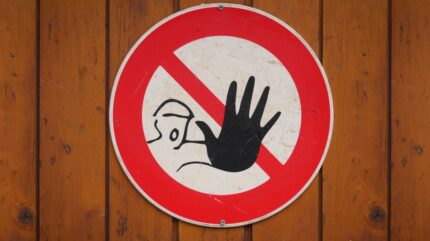 علامت هشدار و دست نگه داشتن روی دیوار چوبی