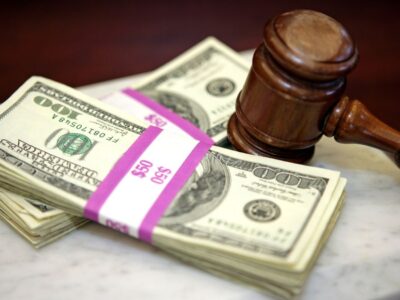 چکش چوبی دادگاه در کنار دسته‌های دلار آمریکا