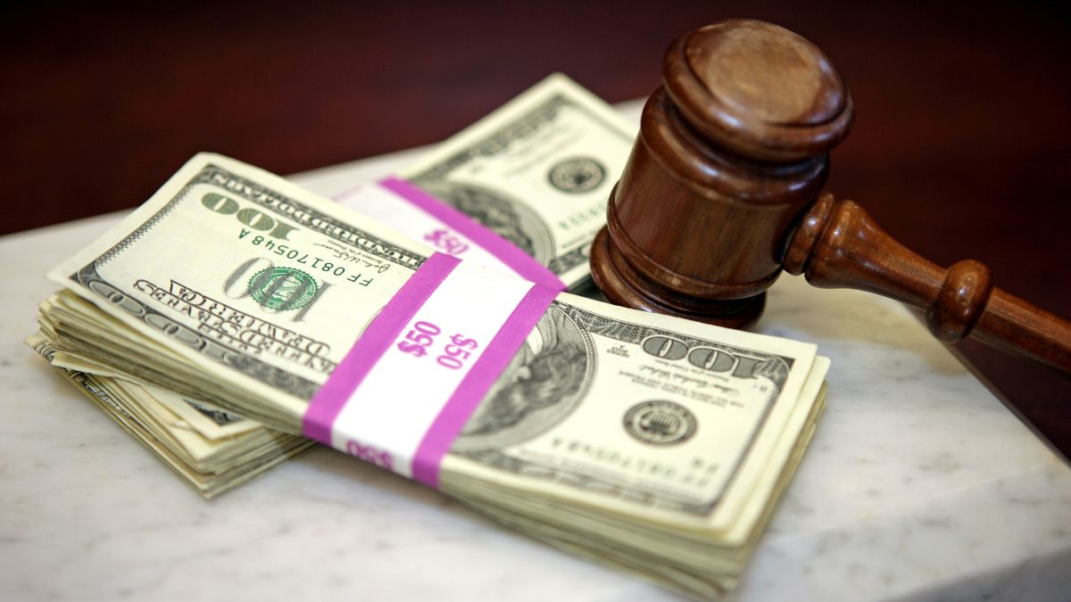 چکش چوبی دادگاه در کنار دسته‌های دلار آمریکا