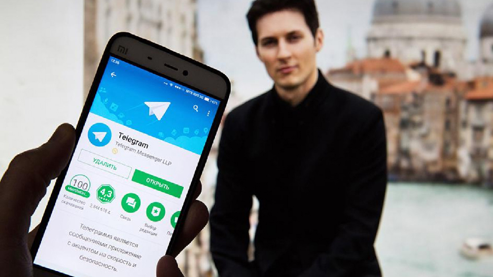 تصویر گوشی موبایل و اپلیکیشن تلگرام و پاول دورف در پس زمینه