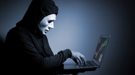 یک هکر با نقاب سید در حال کار با لپ‌تاپ است.