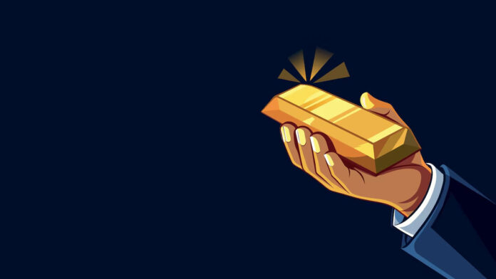 یک دست که شمش طلا را در مشت خود دارد.